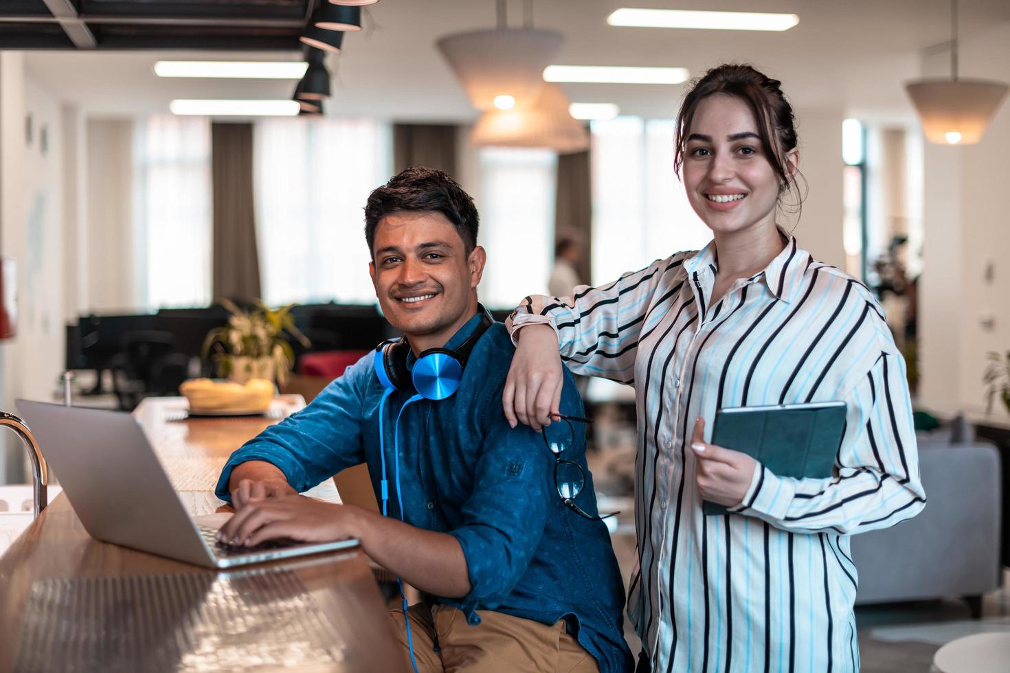 Multiethnic business people man with a female colleague working together on tablet and laptop computer in relaxation area of modern startup office photo