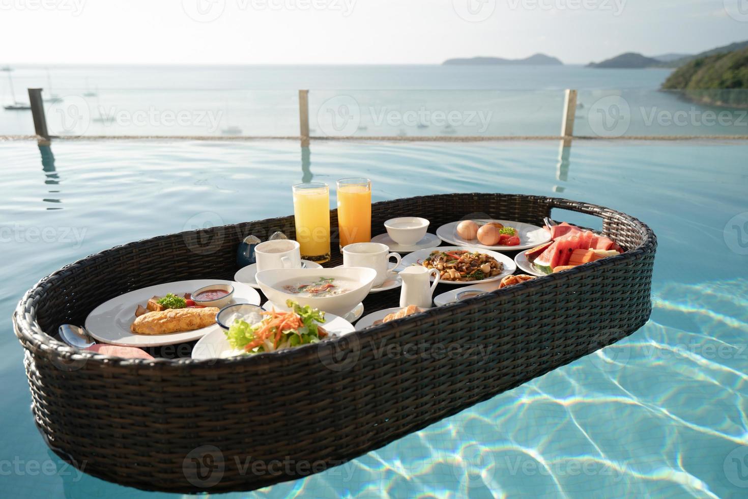 Breakfast set in tray in swimming pool, floating breakfast in tropical resort villa with ocean view. photo