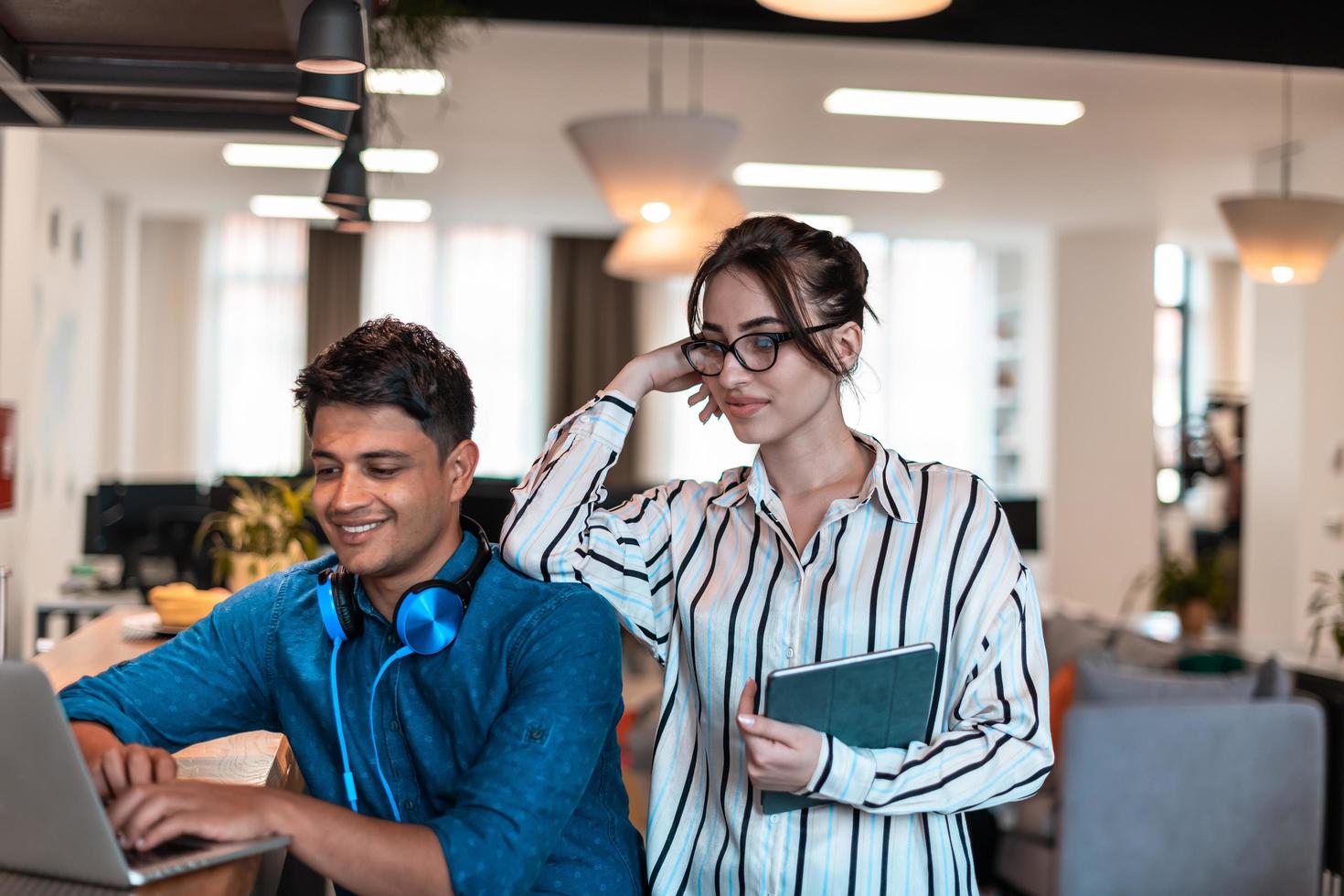 Multiethnic business people man with a female colleague working together on tablet and laptop computer in relaxation area of modern startup office photo