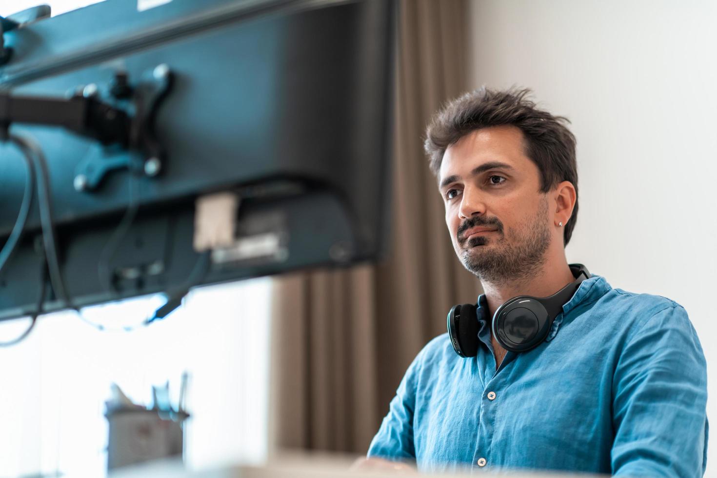 Casual man working on desktop computer in modern open plan startup office interior. Selective focus photo