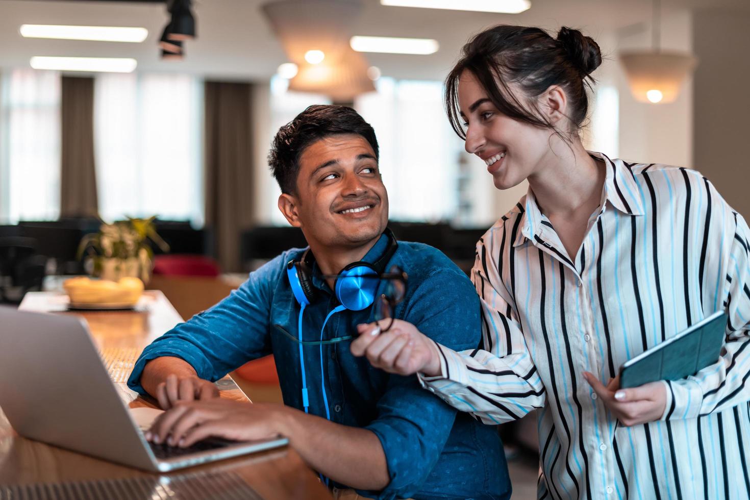 Multiethnic business people man with a female colleague working together on tablet and laptop computer in relaxation area of modern startup office photo