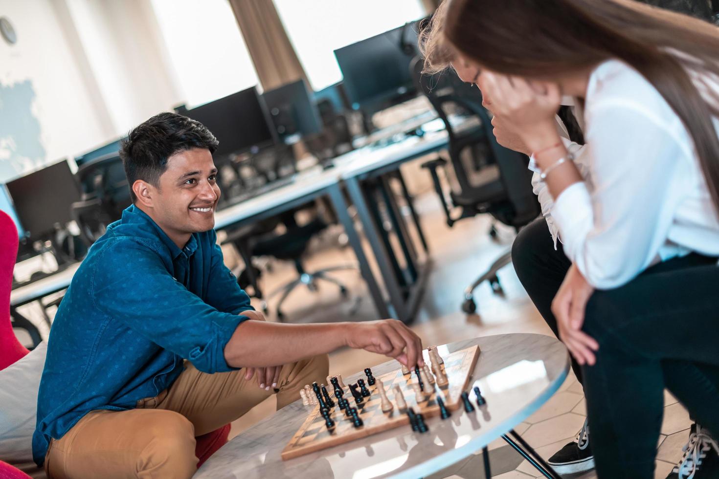 Multiethnic group of business people playing chess while having a break in relaxation area at modern startup office photo