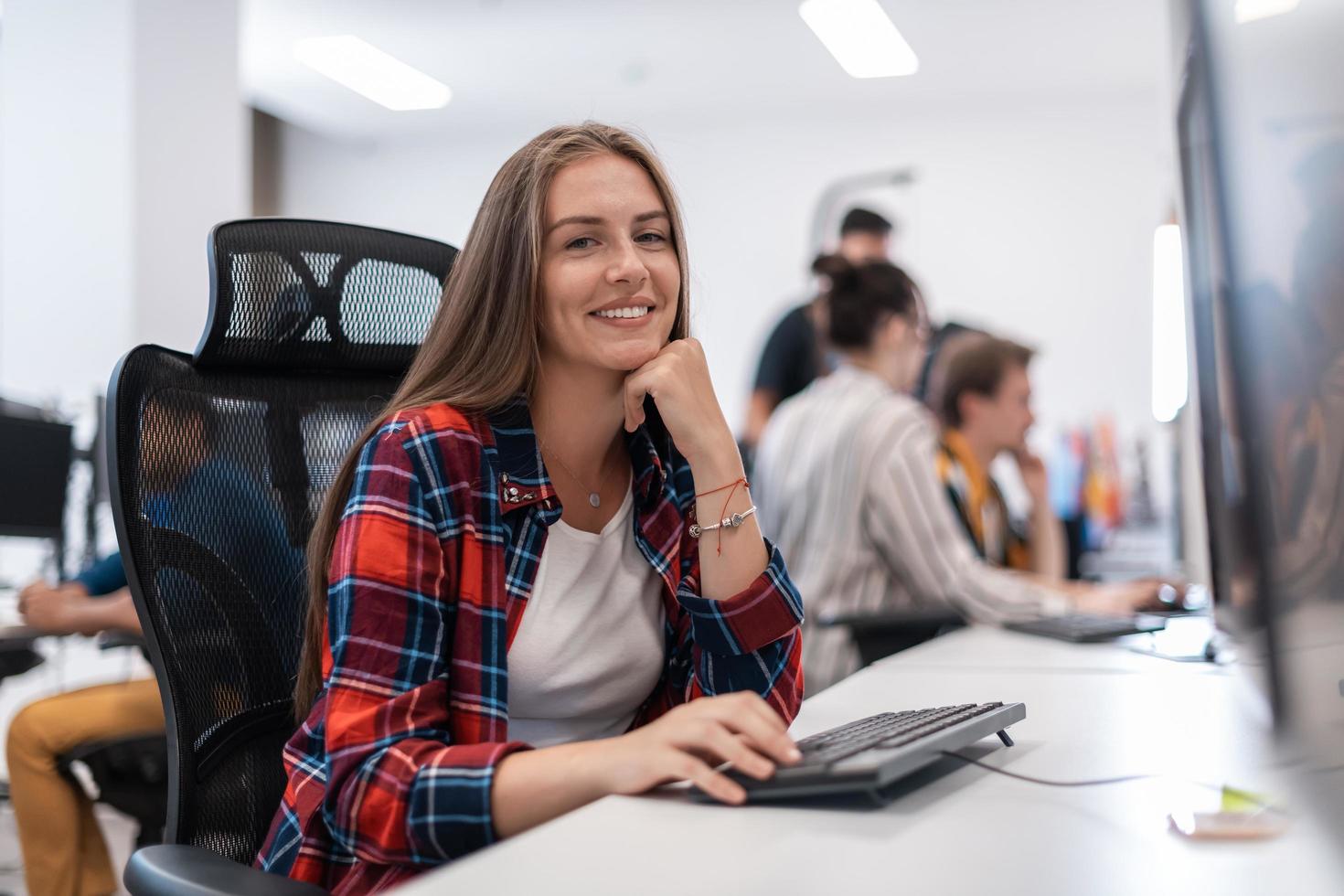 Casual business woman working on desktop computer in modern open plan startup office interior. Selective focus photo