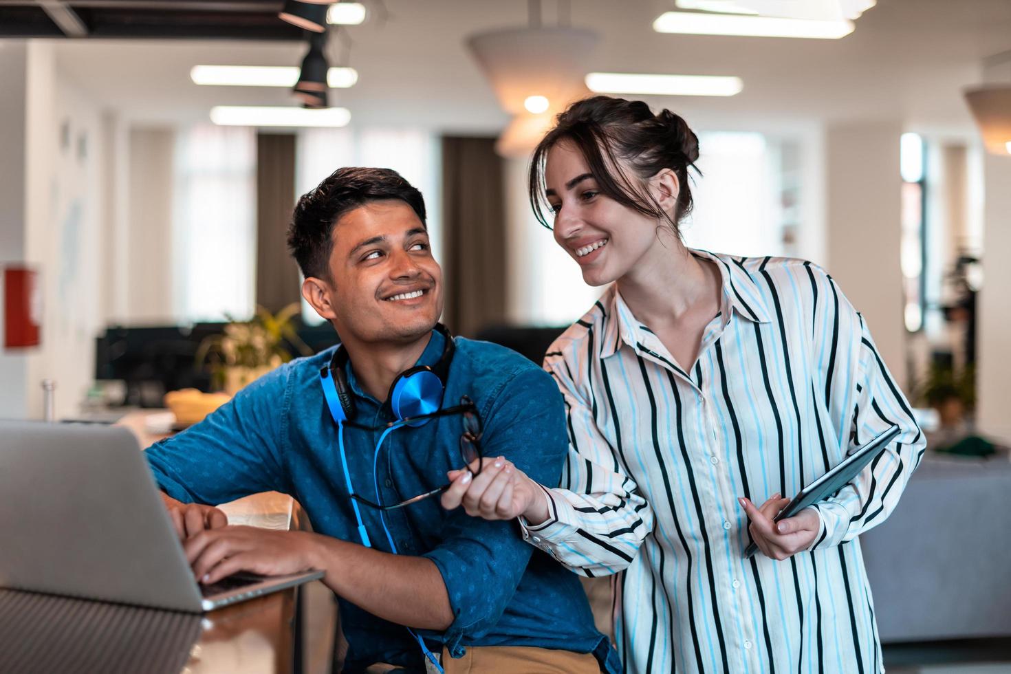 Multiethnic business people man with a female colleague working together on tablet and laptop computer in relaxation area of modern startup office photo