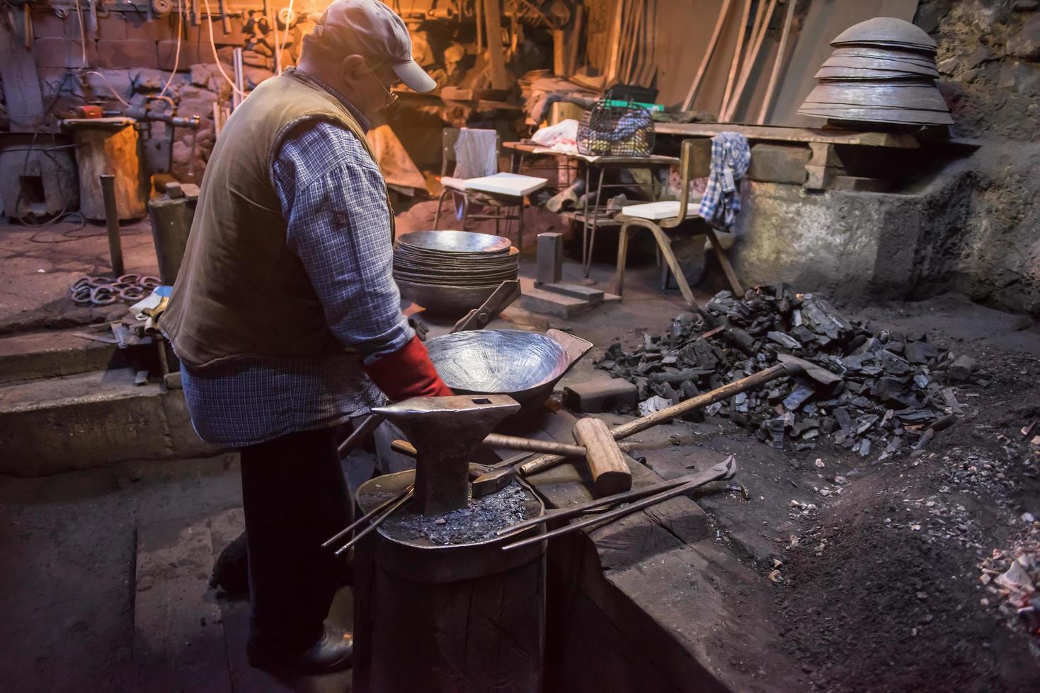 traditional blacksmith manually forging the molten metal photo