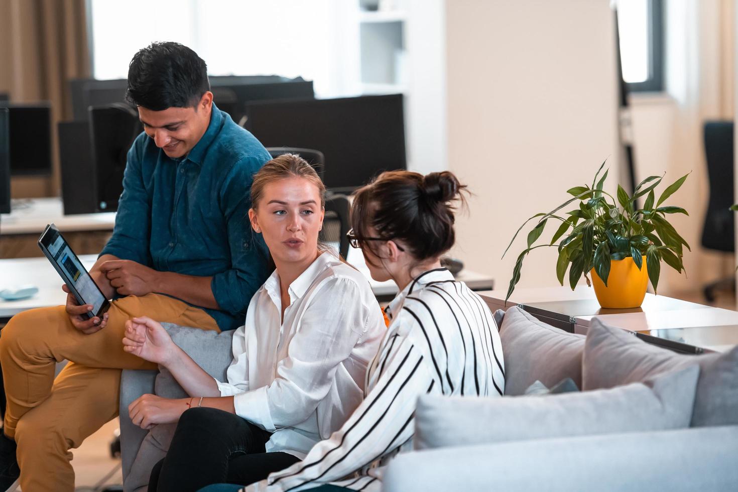 Group of casual multiethnic business people taking break from the work doing different things while enjoying free time in relaxation area at modern open plan startup office photo