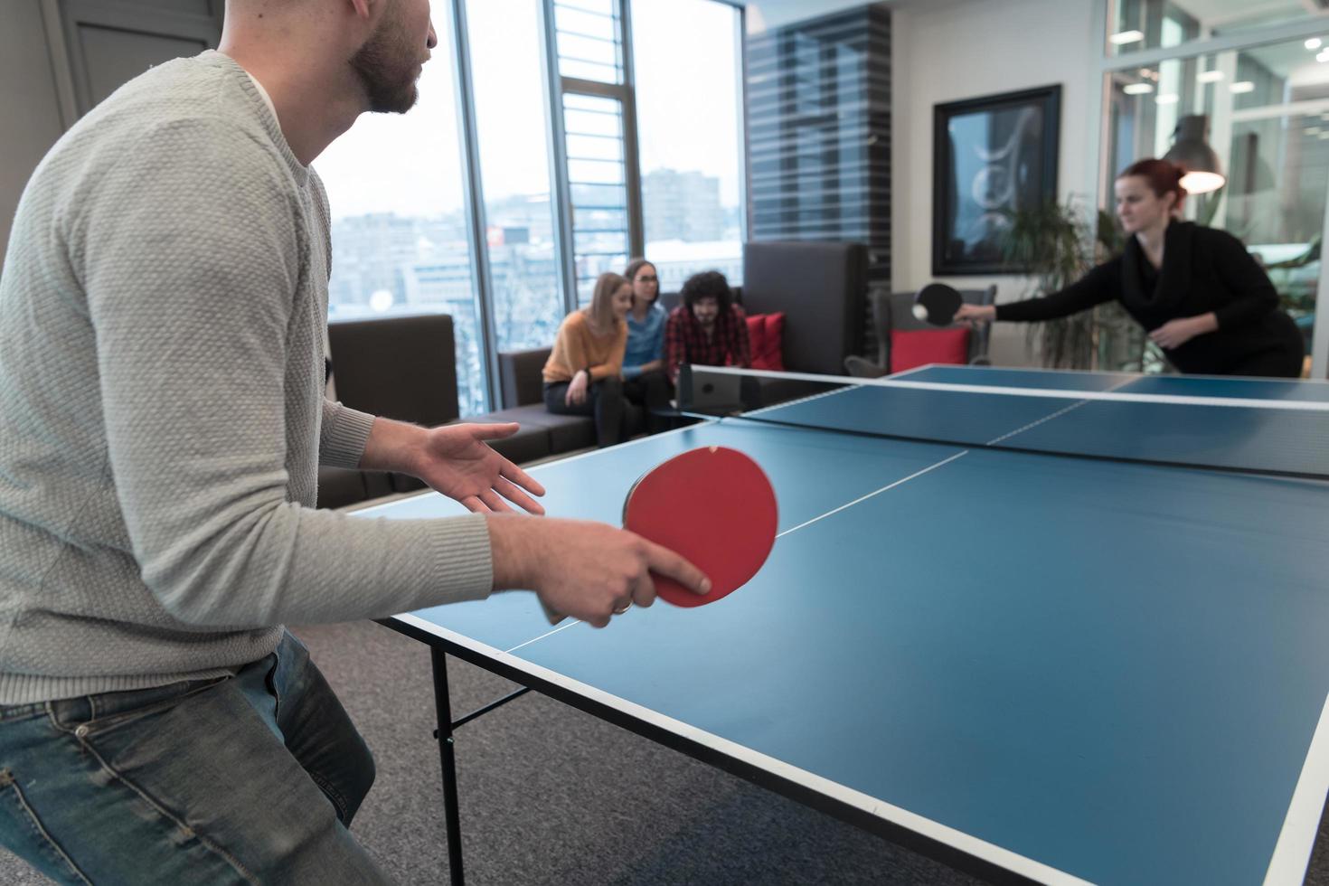 Young start up business man and woman playing table tennis at modern creative office space people group have meeting and brainstorming in background photo