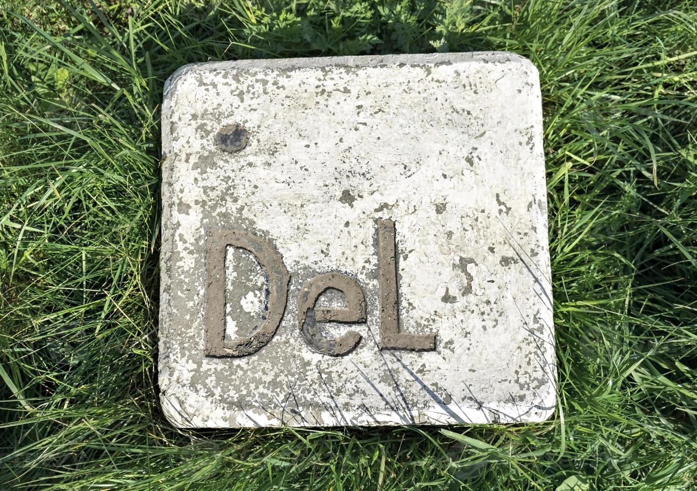 large stone installation button delete makes an imitation computer key lying on the green grass photo