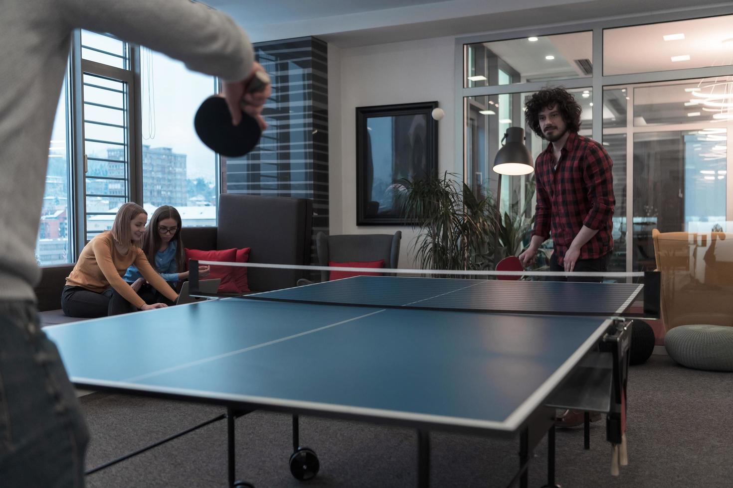 Two young start up business man playing ping pong tennis at modern creative office space people group have meeting and brainstorming in background photo