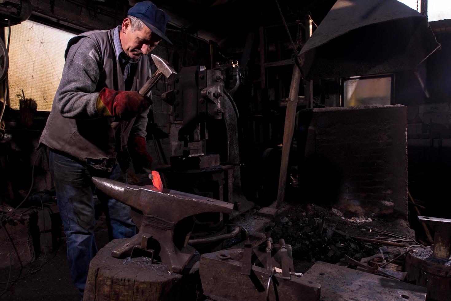 blacksmith manually forging the molten metal photo