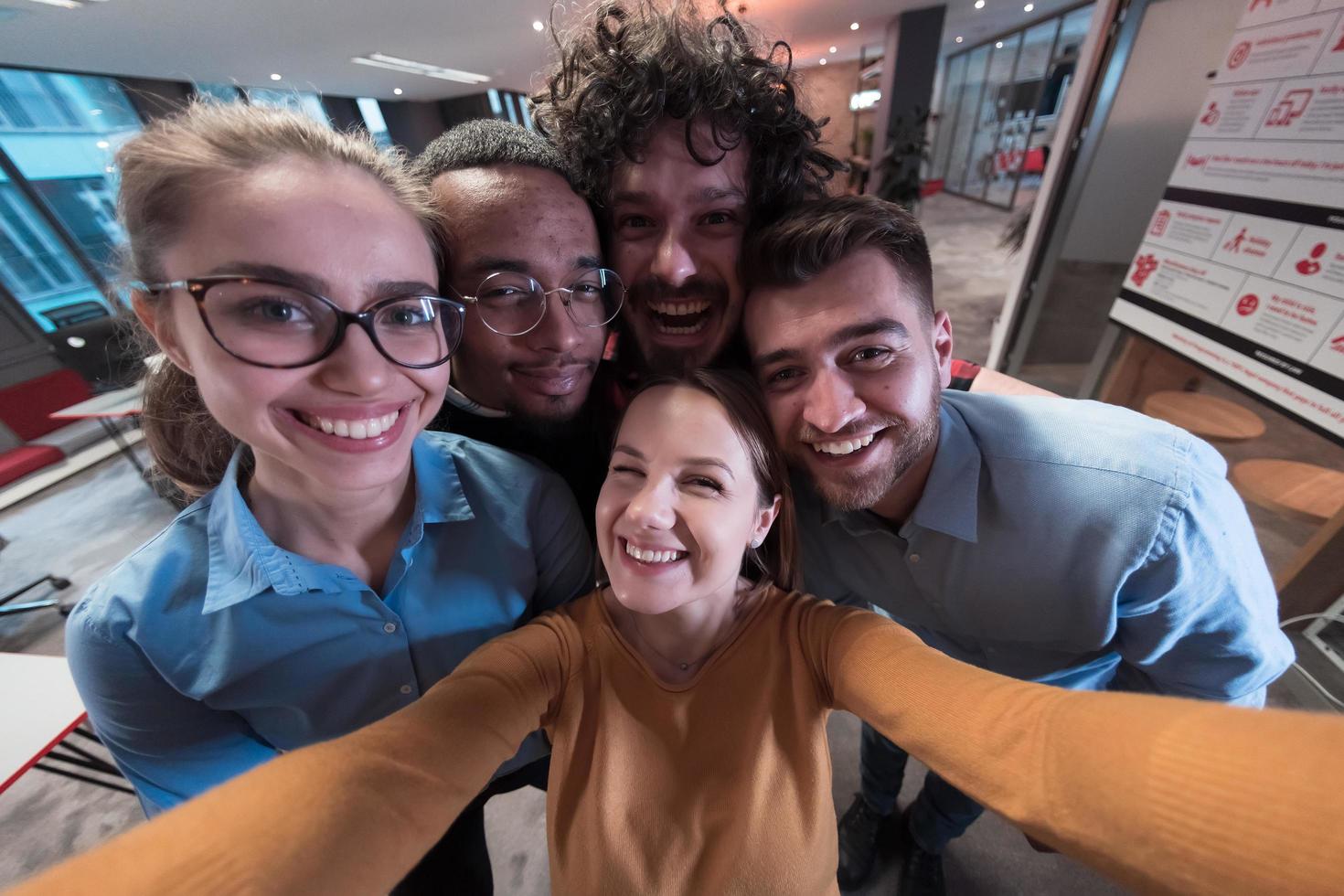 Group of business people during break from the work taking selfie picture while enjoying free time in relaxation area at modern open plan startup office. Selective focus photo