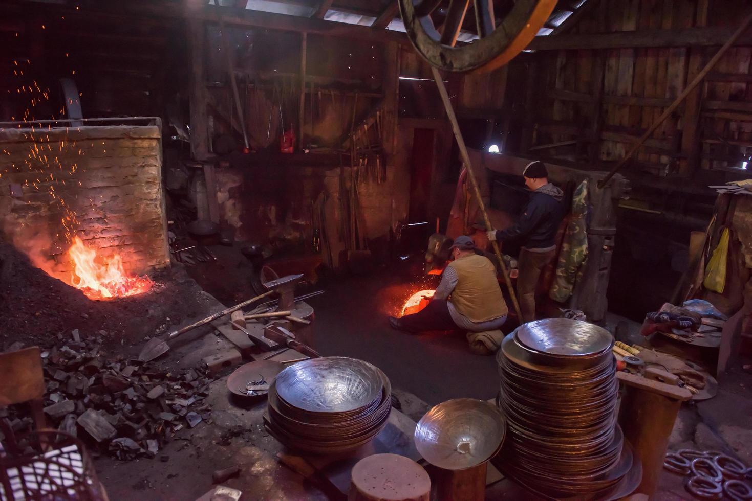 blacksmith workers using mechanical hammer at workshop photo