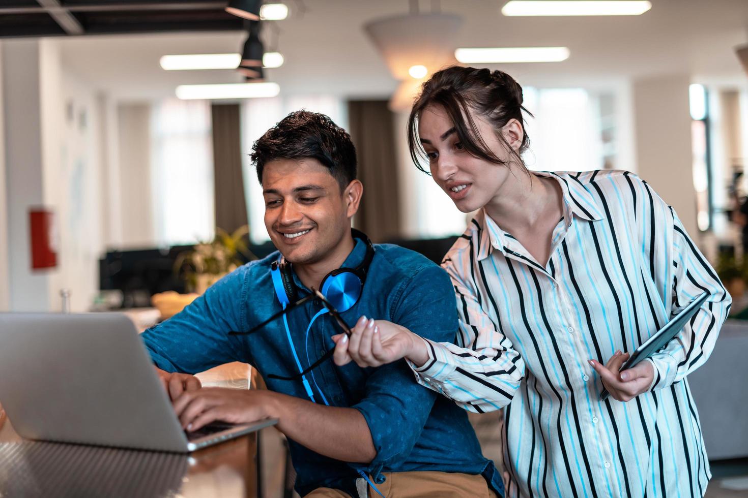 Multiethnic business people man with a female colleague working together on tablet and laptop computer in relaxation area of modern startup office photo