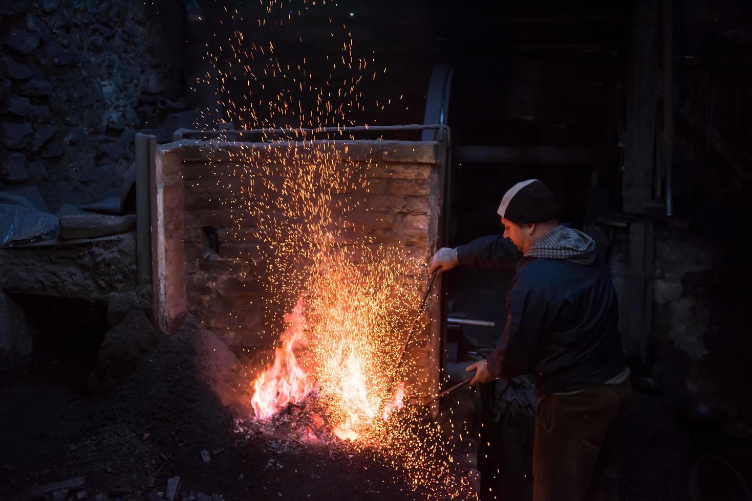 young traditional Blacksmith working with open fire photo