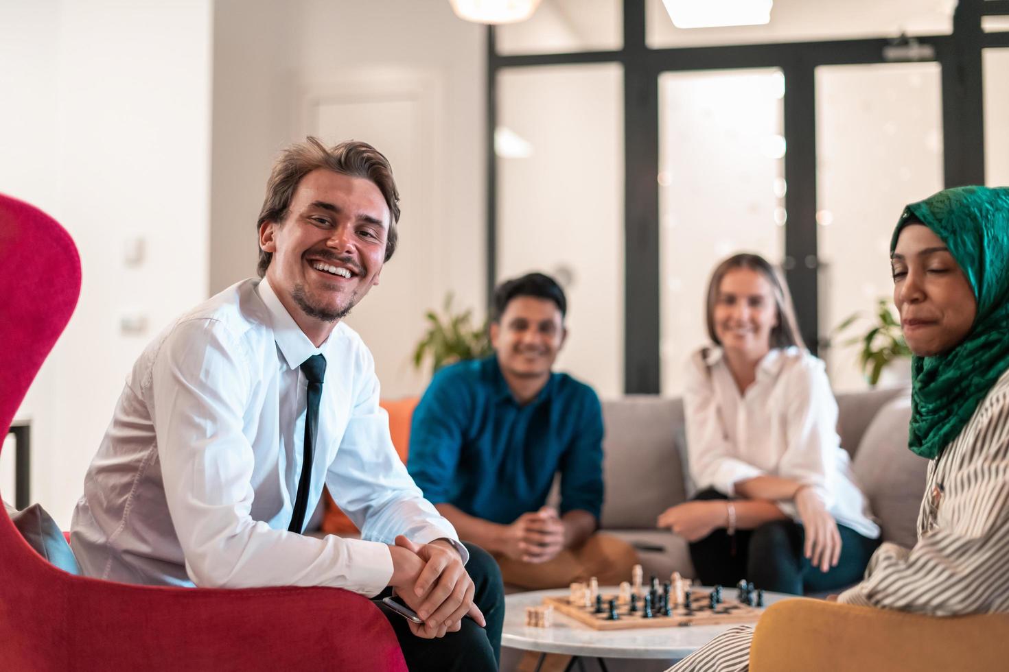 Multiethnic group of business people playing chess while having a break in relaxation area at modern startup office. photo