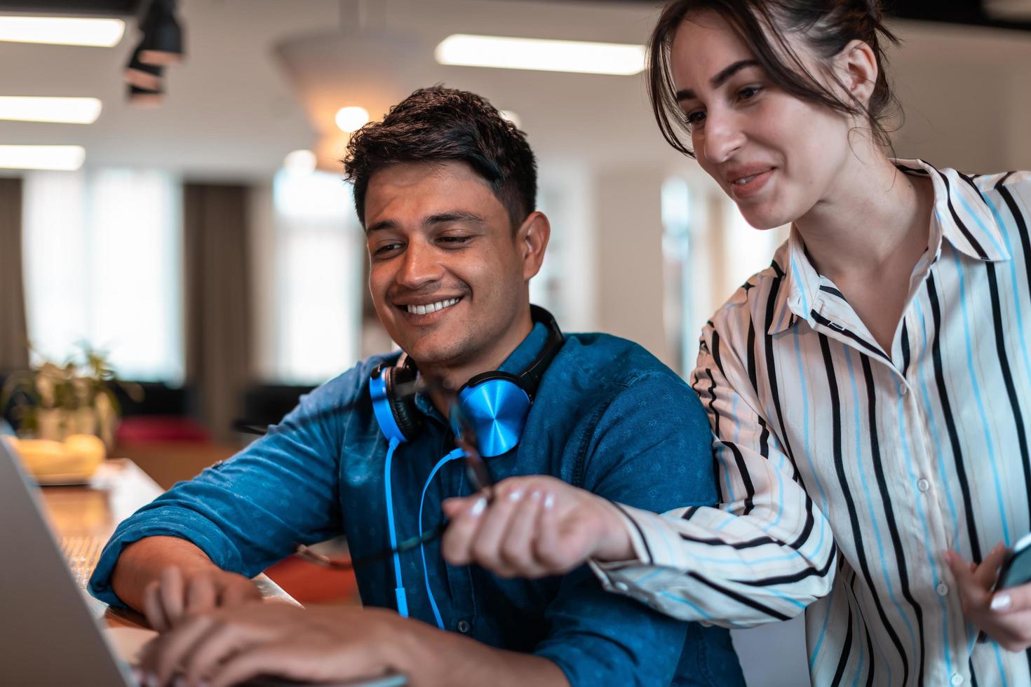 Multiethnic business people man with a female colleague working together on tablet and laptop computer in relaxation area of modern startup office photo