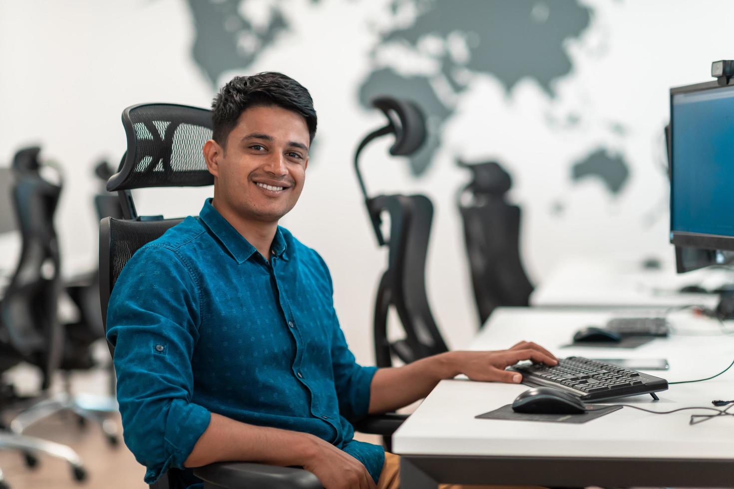 Casual business man working on desktop computer in modern open plan startup office interior. Selective focus photo