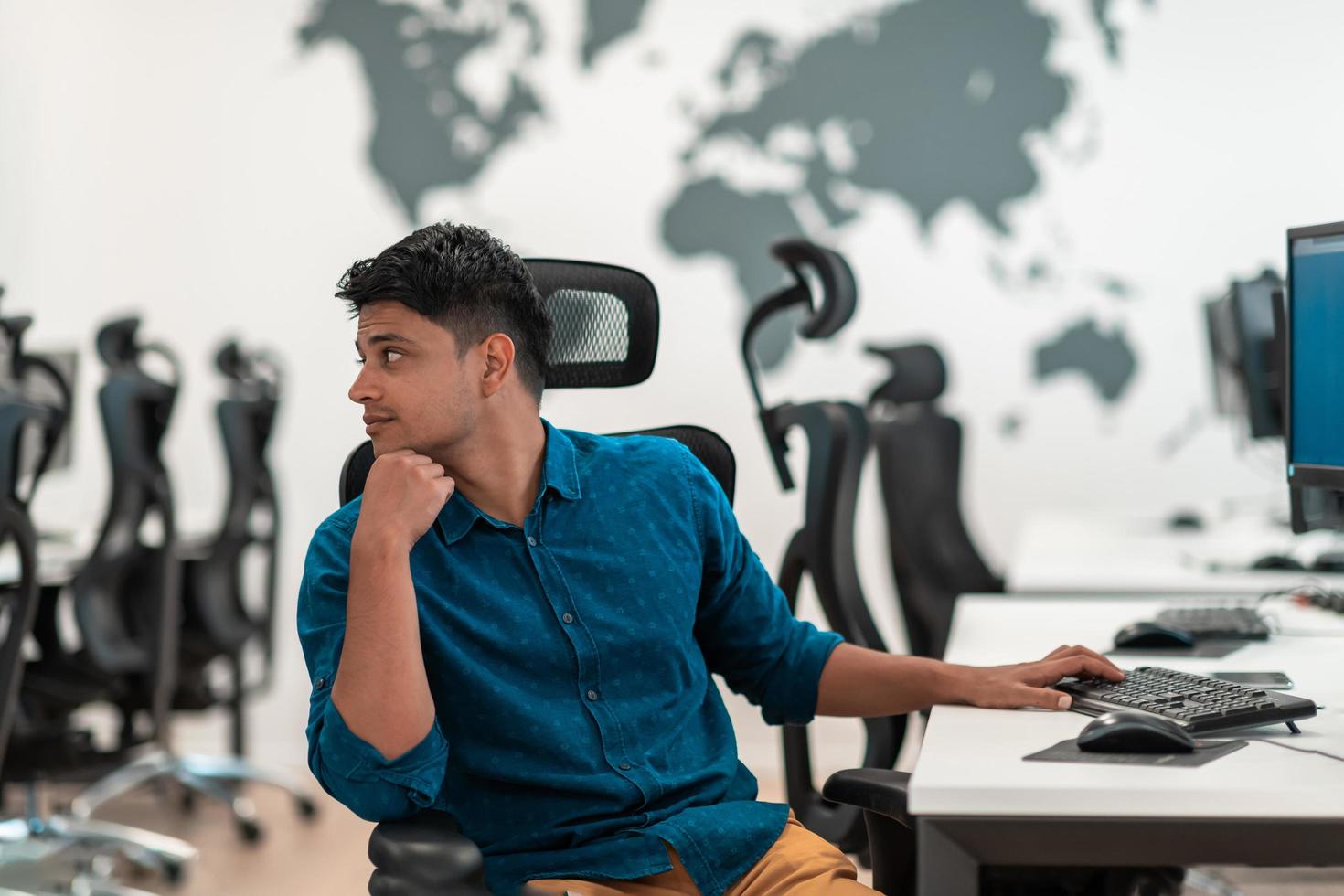 Casual business man working on desktop computer in modern open plan startup office interior. Selective focus photo