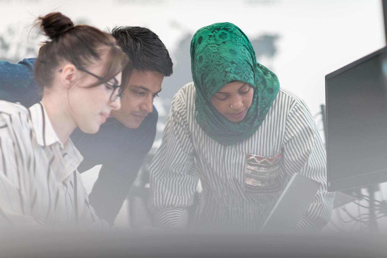 Multiethnic startup business team woman wearing a hijab on meeting in modern open plan office interior brainstorming, working on laptop and desktop computer. Selective focus photo