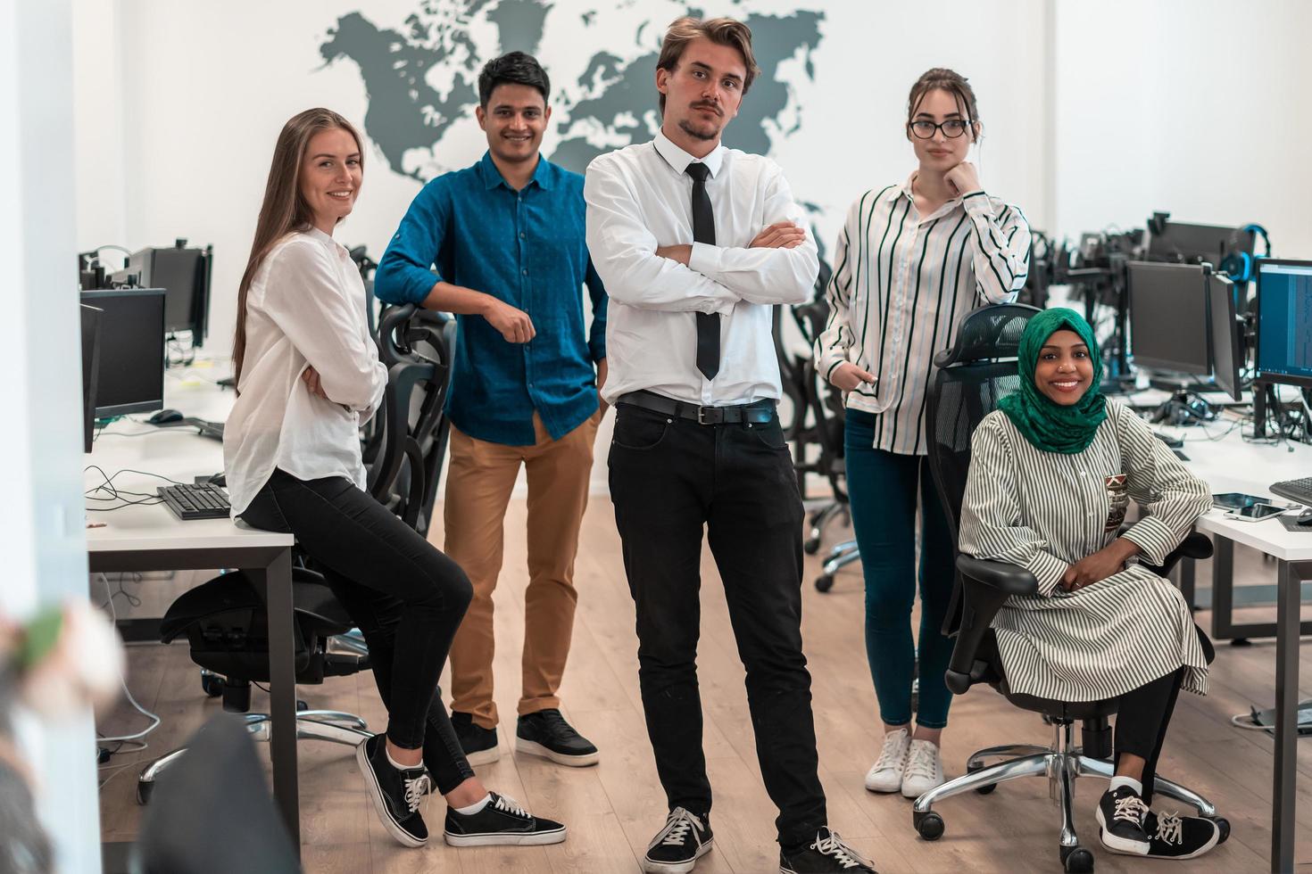 Portrait of young excited multiethnics business team of software developers standing and looking at camera at modern startup office photo