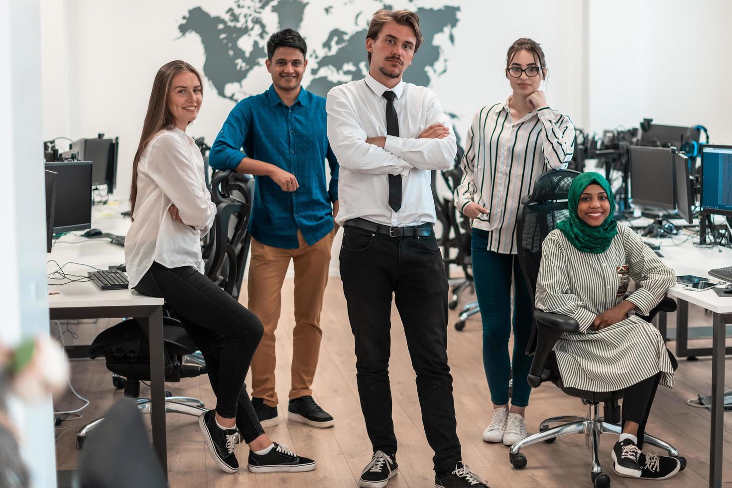 retrato de un joven equipo de negocios multiétnico emocionado de desarrolladores de software de pie y mirando la cámara en la oficina de inicio moderna foto