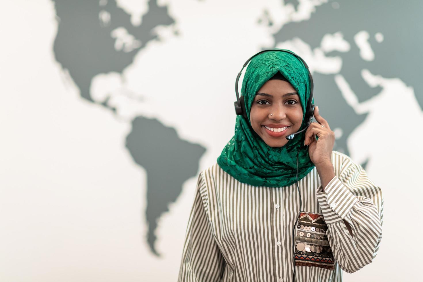 mujer afro musulmana con bufanda hijab verde representante del cliente mujer de negocios con auriculares de teléfono ayudando y apoyando en línea con el cliente en un centro de llamadas moderno foto