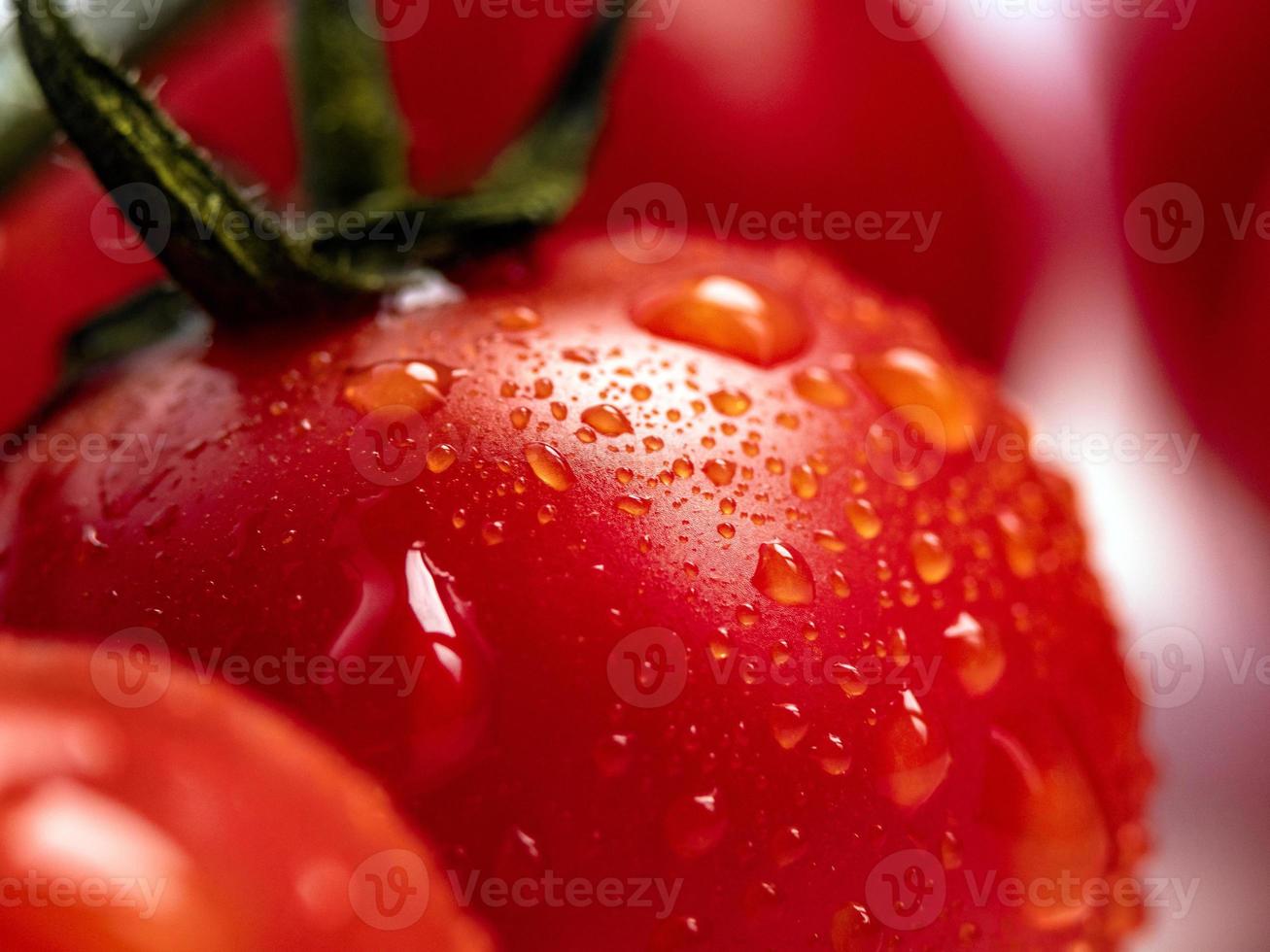 Fotografía macro de tomate cherry rojo fresco con gotas de agua foto