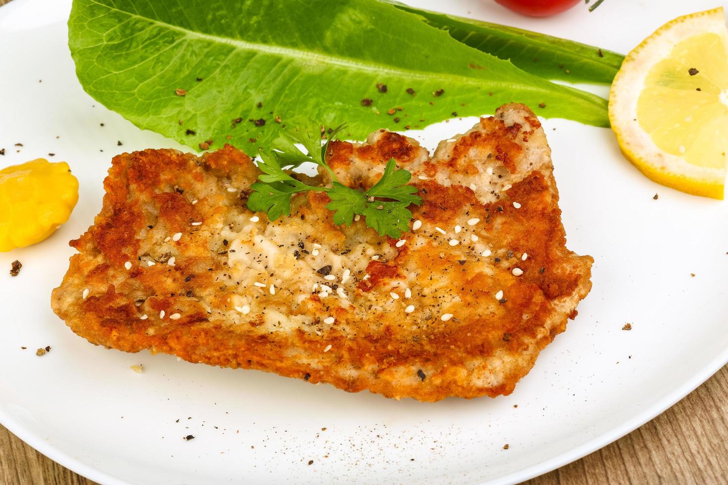 Pork schnitzel on the plate and wooden background photo
