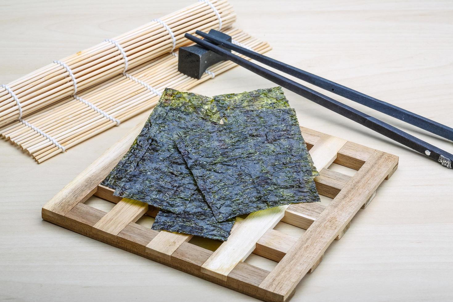 Nori sheets on wooden board and wooden background photo