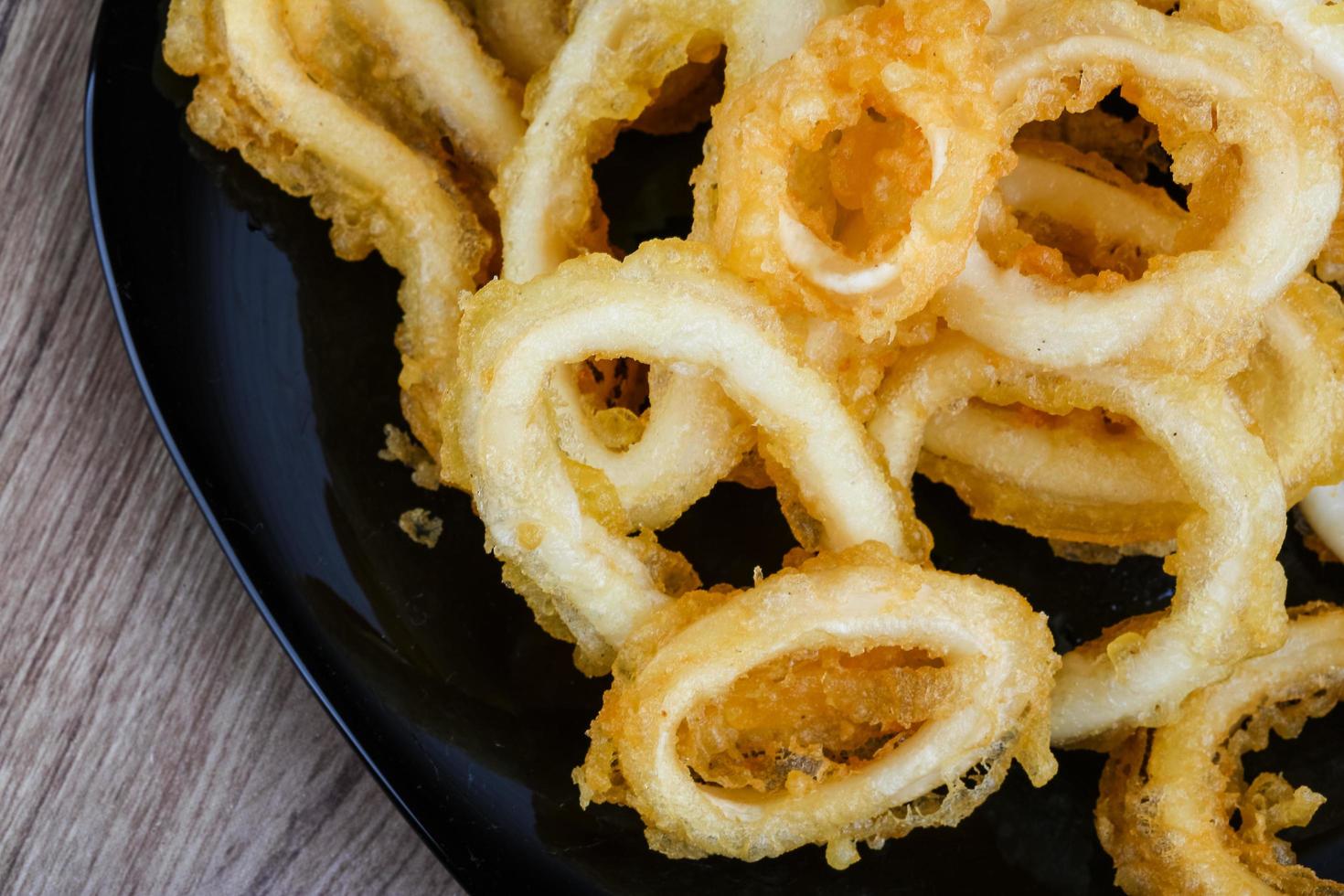 Squid rings on the plate and wooden background photo