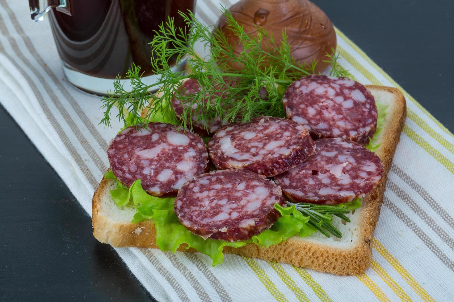 Sándwich de salami sobre fondo de madera foto