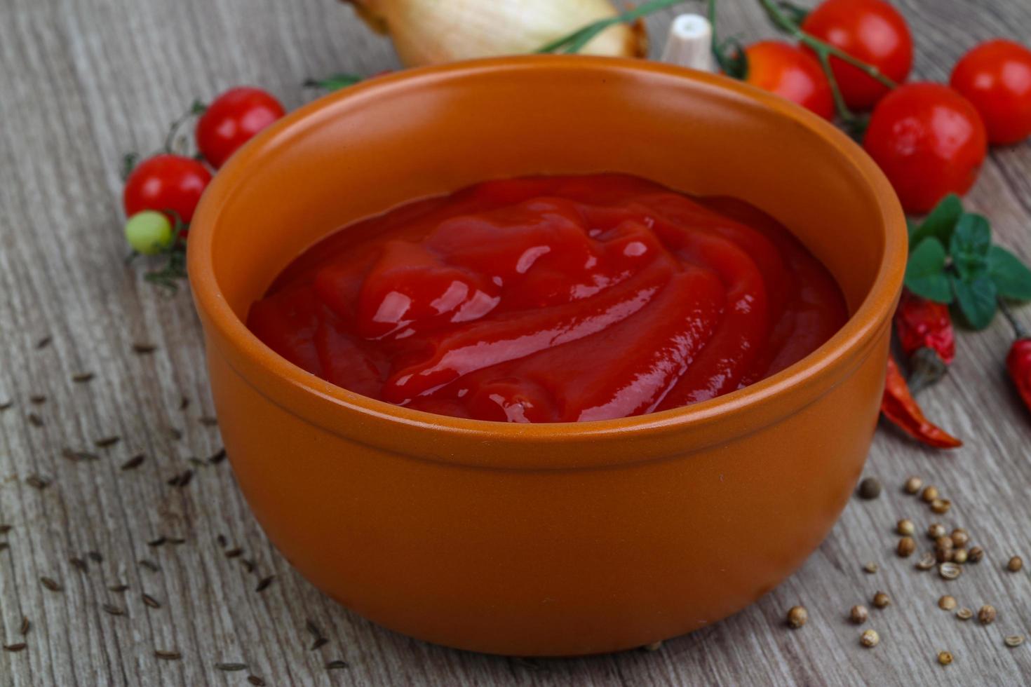 ketchup de tomate en un recipiente sobre fondo de madera foto