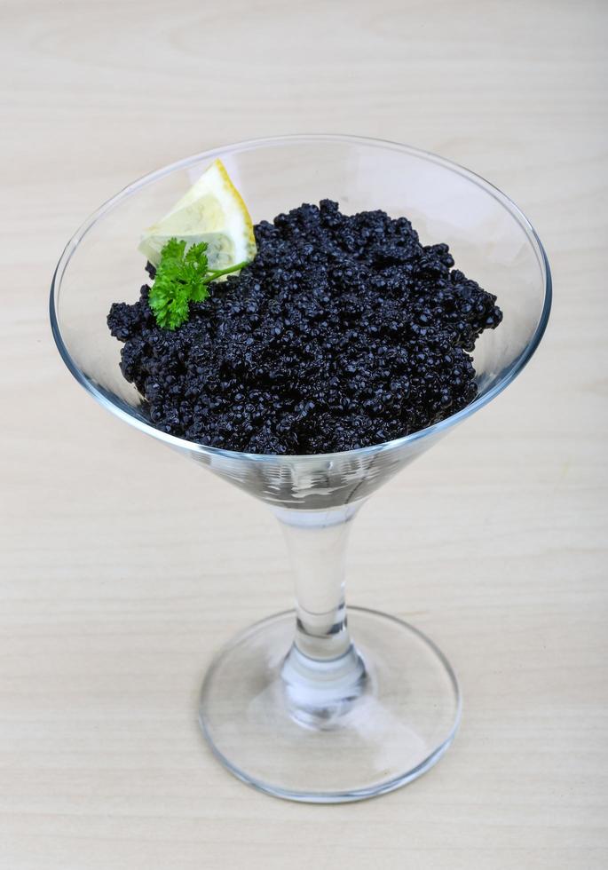 Black caviar in a bowl on wooden background photo