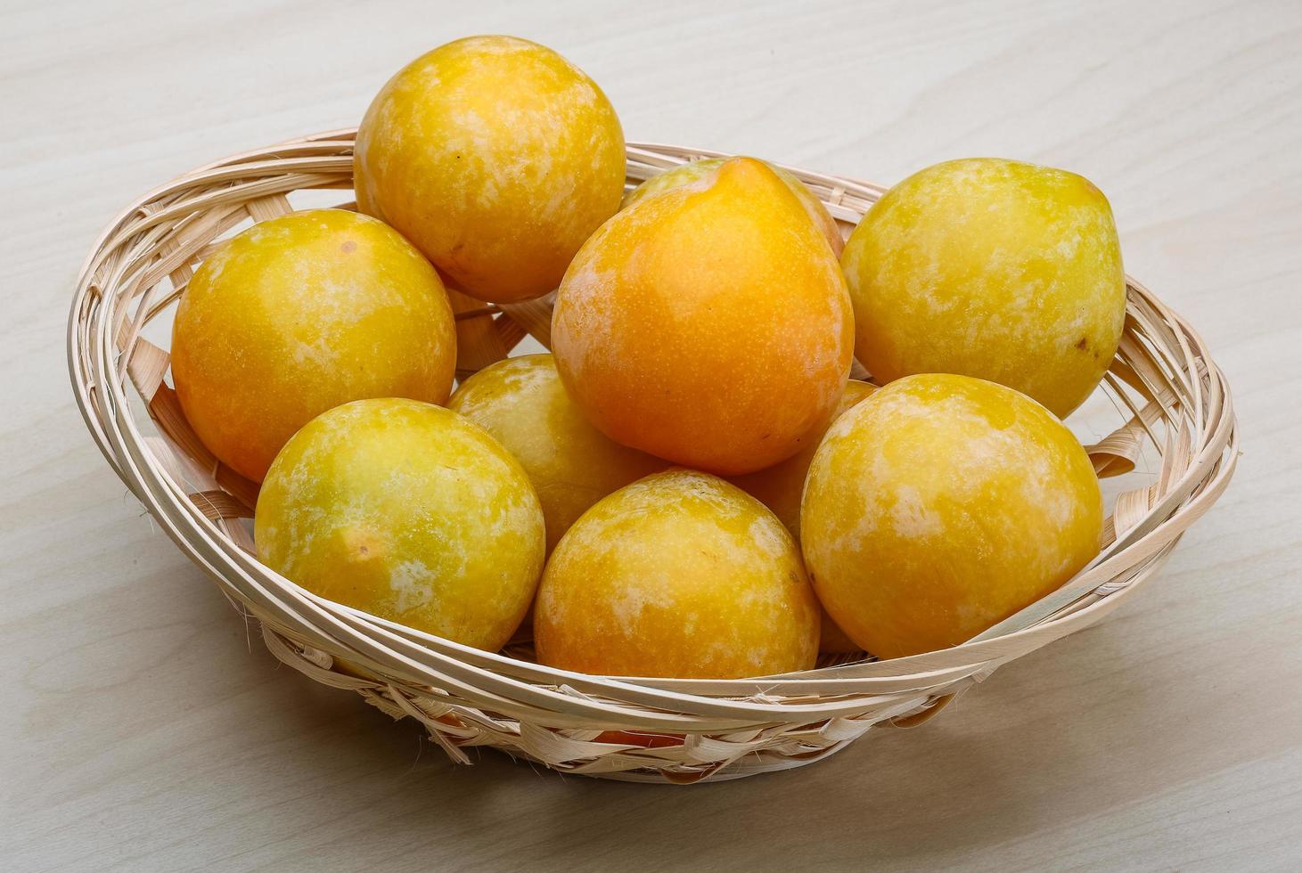 Yellow plums in a basket on wooden background photo