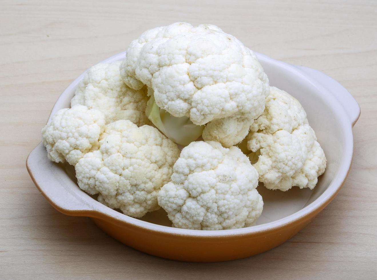 Cauliflower in a bowl on wooden background photo