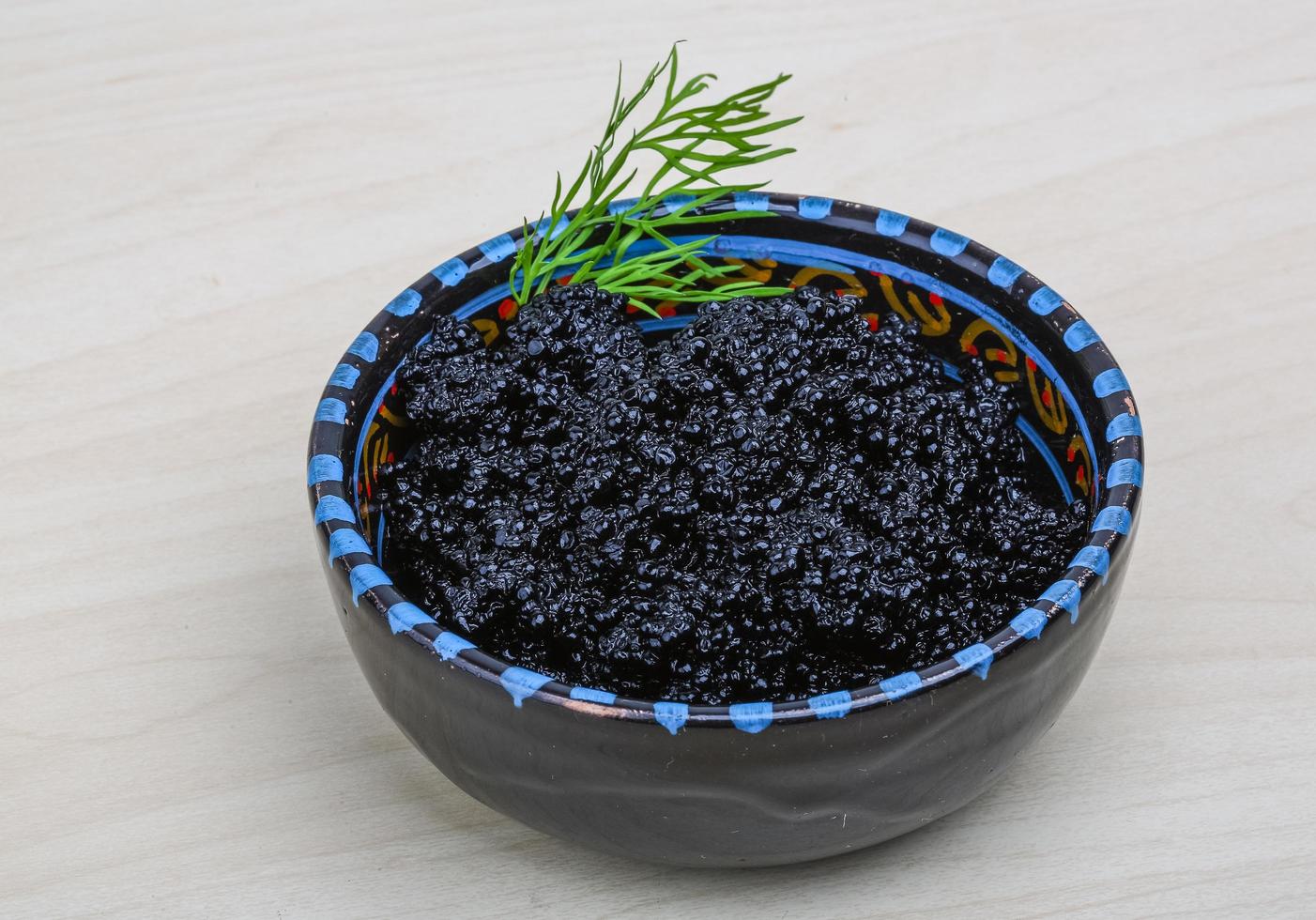 Black caviar in a bowl on wooden background photo