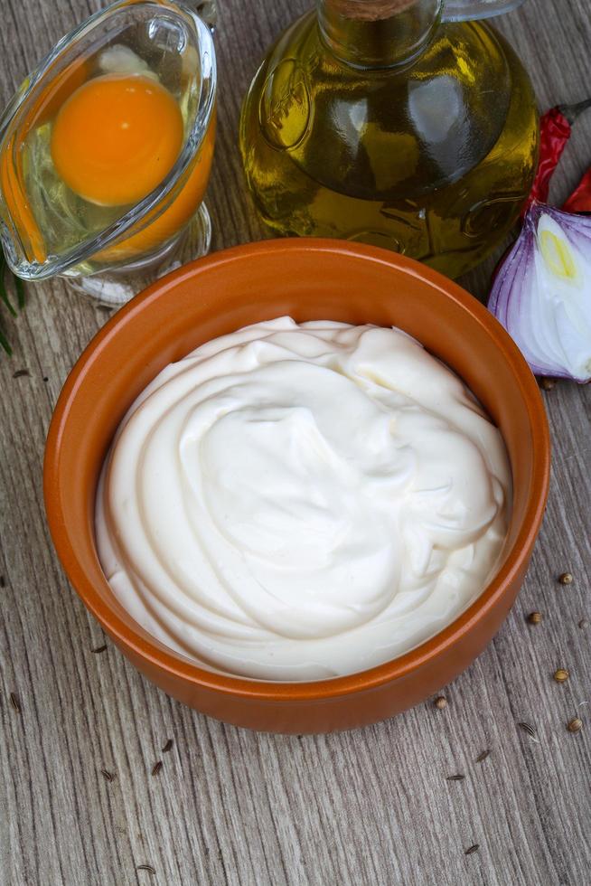 Mayonnaise sauce in a bowl on wooden background photo