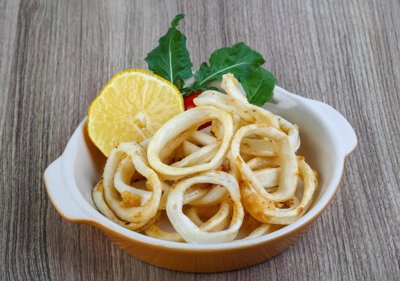 Squid rings in a bowl on wooden background photo