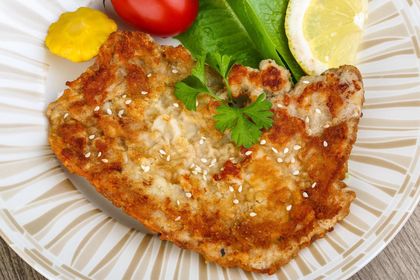 Pork schnitzel on the plate and wooden background photo
