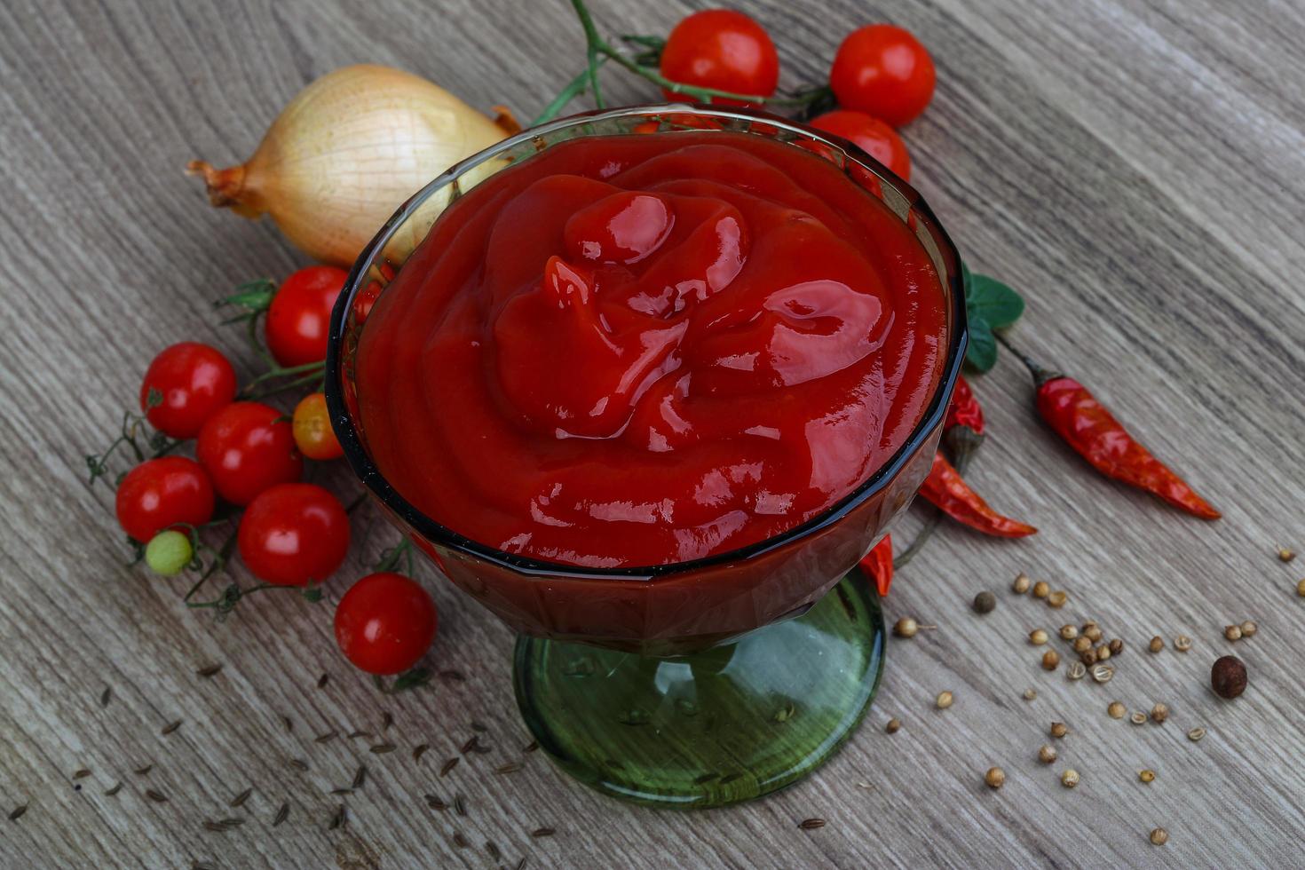Tomato ketchup in a bowl on wooden background photo