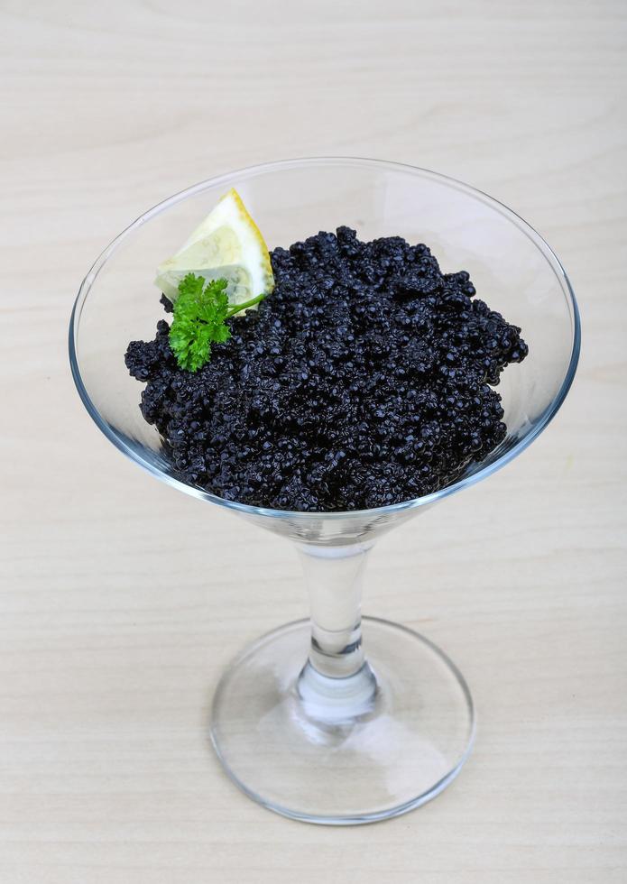 Black caviar in a bowl on wooden background photo