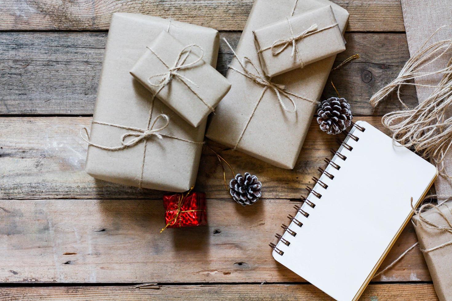 christmas gift box Use brown recycled paper and a notebook and pine cones on a wooden table. photo