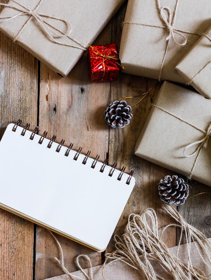 christmas gift box Use brown recycled paper and a notebook and pine cones on a wooden table. photo