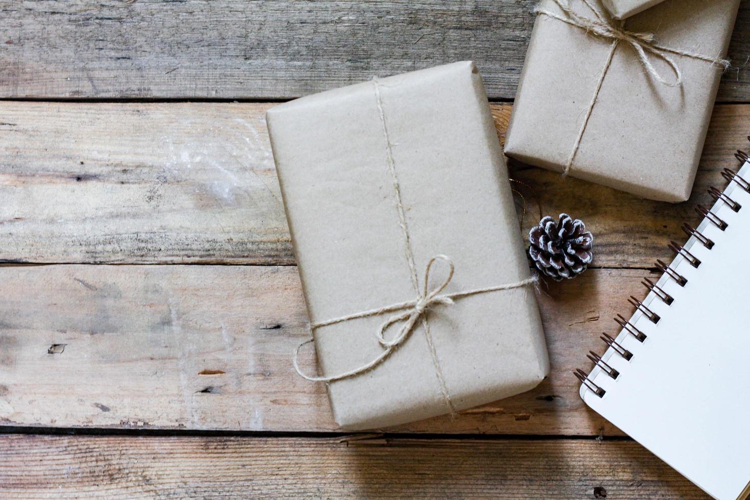 christmas gift box Use brown recycled paper and a notebook and pine cones on a wooden table. photo