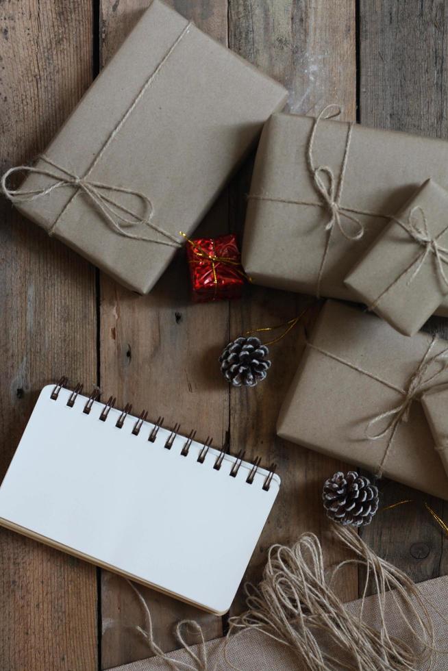 christmas gift box Use brown recycled paper and a notebook and pine cones on a wooden table. photo