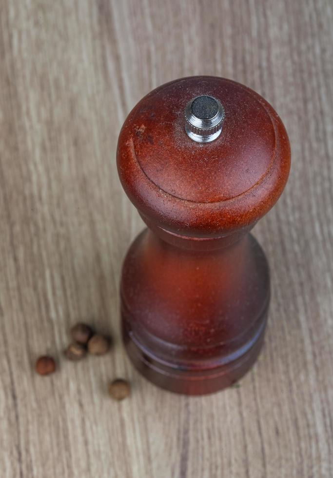 Pepper mill on wooden background photo