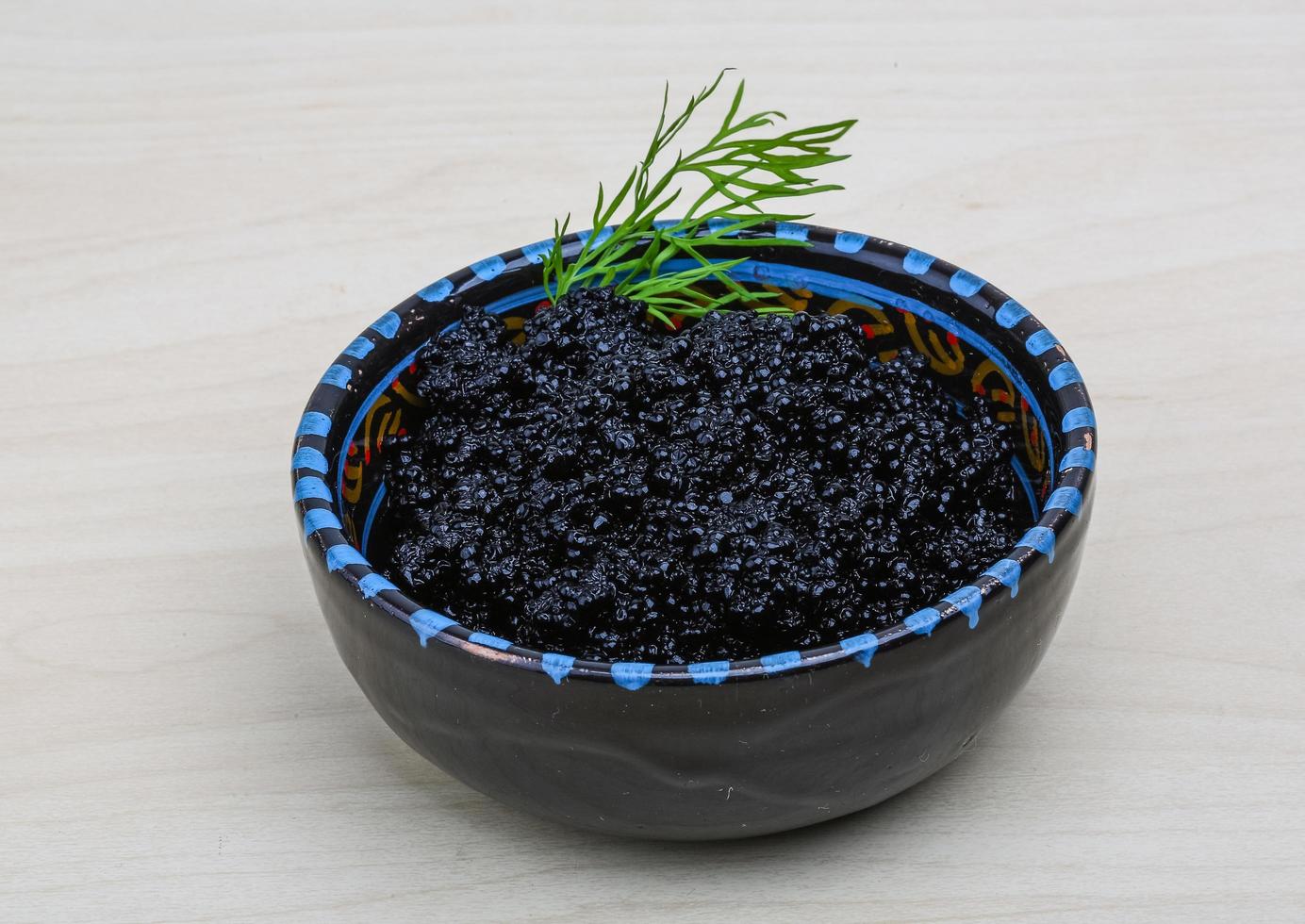Black caviar in a bowl on wooden background photo