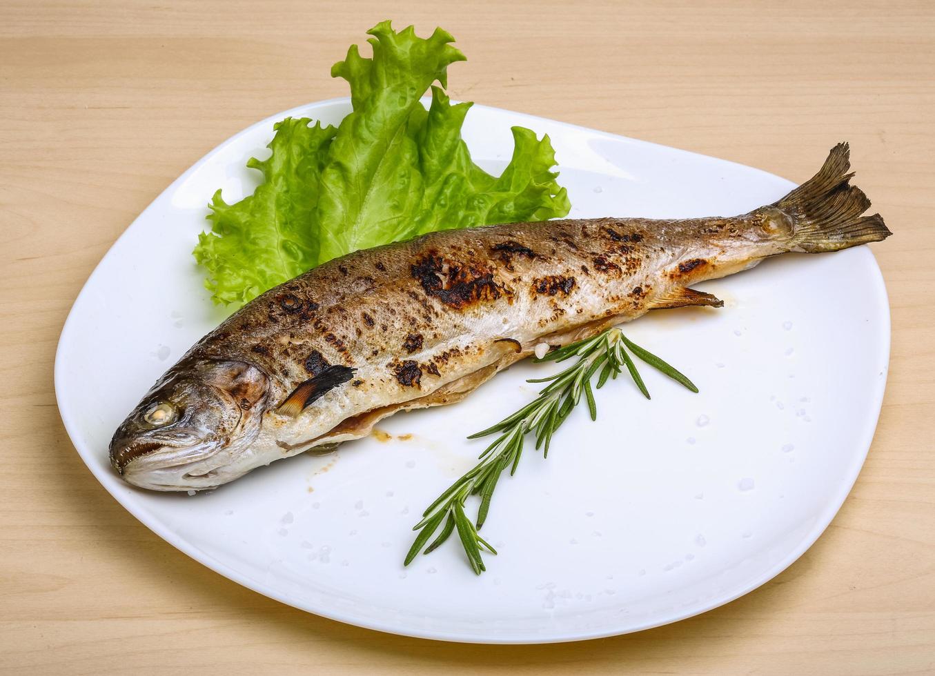 Grilled trout on the plate and wooden background photo