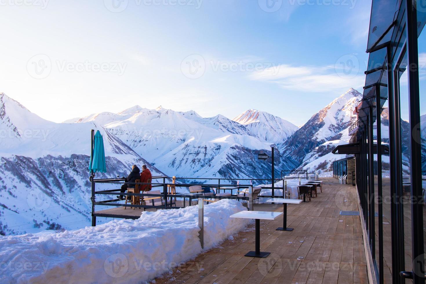 Couple together sit enjoy sunset in winter ski resort with snowy peaks background. Valentines day in winter concept. Togetherness connection concept photo