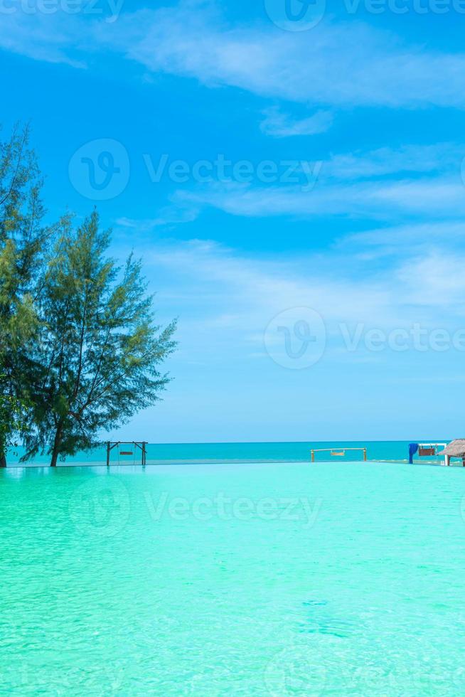 beautiful swimming pool with coconut palm tree and sea background photo